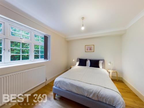 a bedroom with a bed and two windows at Redhill town centre apartment by Livingo in Redhill