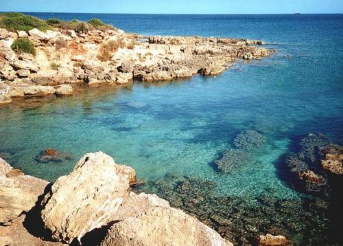 a large body of water with rocks and the ocean at Sweet Home & Apartments in Fontane Bianche