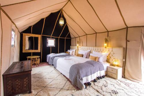 a bedroom with two beds in a tent at Luxury Camp desert Maroc Tours in Mhamid