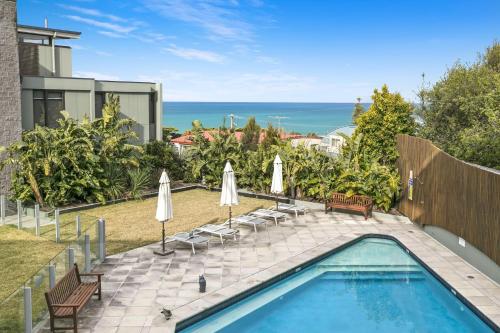 ローンにあるLorne Chalet Apartment 29の椅子とパラソルのあるプールと海