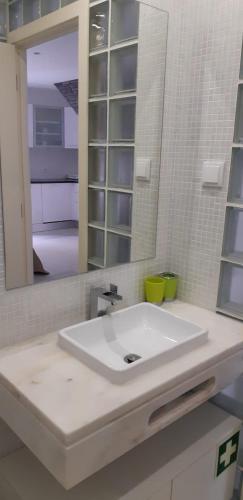 a bathroom with a white sink and a mirror at Zimbra Blue Apartment in Sesimbra