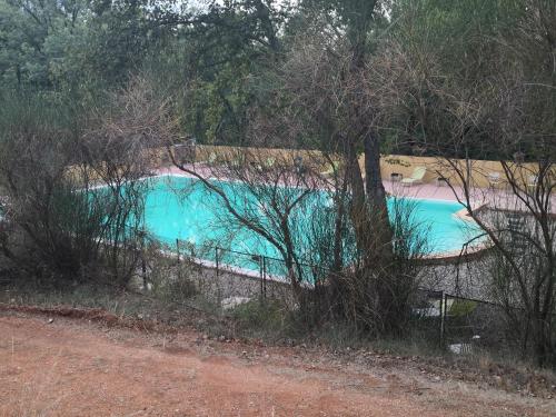 een blauw zwembad met een hek eromheen bij La Colline des Ocres Village de vacances 3 étoiles in Apt