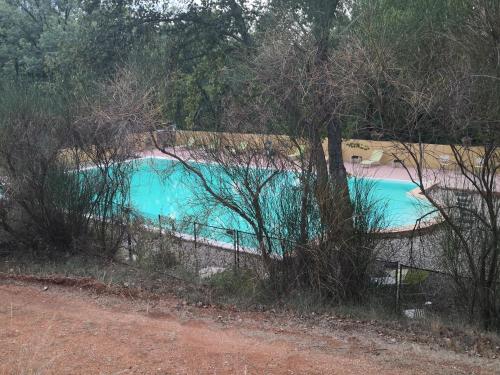 a blue swimming pool with a fence around it at La Colline des Ocres Village de vacances 3 étoiles in Apt