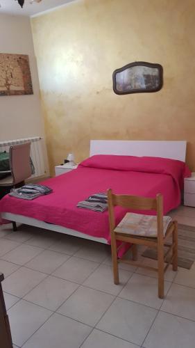 a bedroom with a bed with pink sheets and a chair at Appartamento e Attico Epi in Lucca Sicula