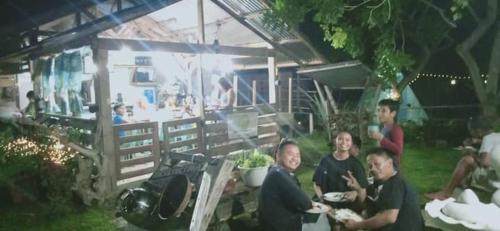 a group of people sitting in the grass in a yard at House of TamSe Laagans ' Inn in Badian