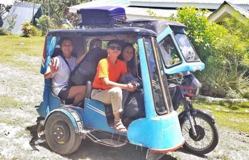a group of people sitting in a golf cart at House of TamSe Laagans ' Inn in Badian