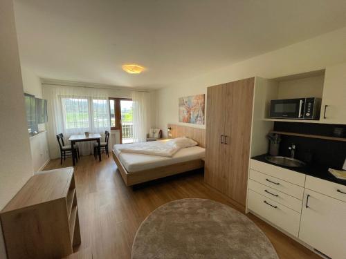 een slaapkamer met een bed en een keuken met een tafel bij Gasthaus Hirschenstube & Gästehaus Gehri in Waldkirch