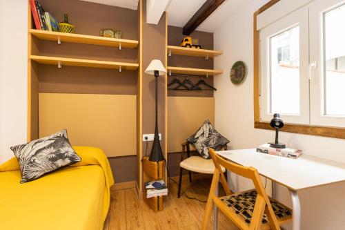 バルセロナにあるApartEasy - Central Gracia Apartmentsの黄色のベッドとデスクが備わる客室です。