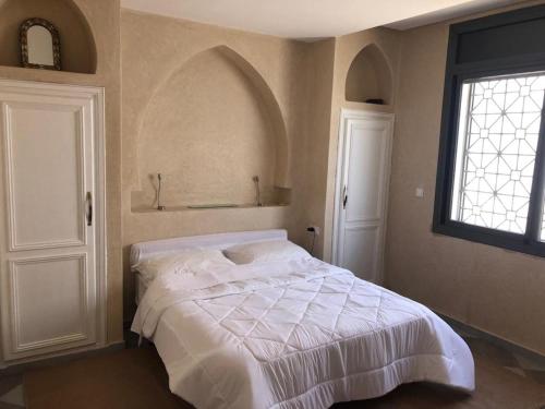 een slaapkamer met een wit bed en een raam bij villa blanche tifnit in Tifnit