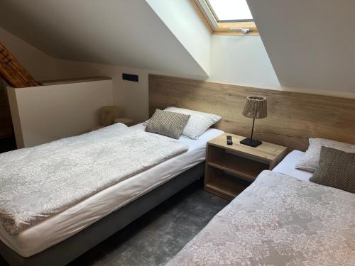 a bedroom with two beds and a lamp on a night stand at Penzion a Restaurace ZÁMECKÁ VRÁTNICA in Vizovice