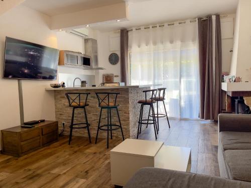 a living room with a couch and a bar with stools at Appartement Maenat in Borgo