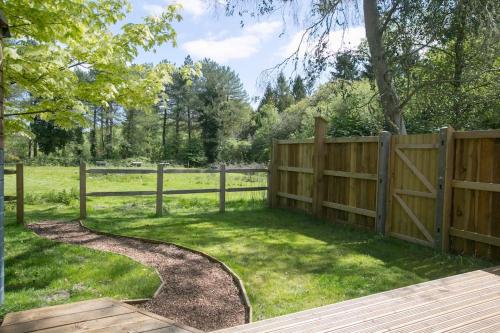 a wooden fence in a field with a yard at Sky Cabin. Cosy Forest Log Cabin 3 night minimum in Wareham