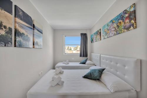 ein weißes Schlafzimmer mit 2 Betten und einem Fenster in der Unterkunft SUN GOLF, Heated Pool, 3 Rooms, Air Cond in San Miguel de Abona