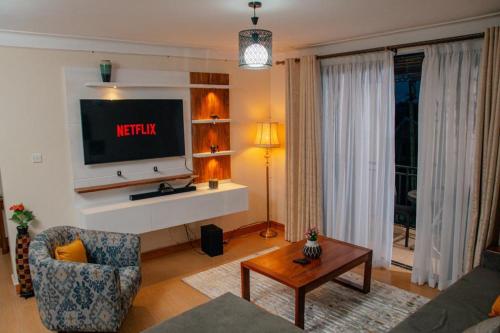 a living room with a television on a wall at Broadbills Haven apartment in Kampala