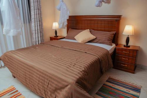 a bedroom with a large bed with two night stands at Broadbills Haven apartment in Kampala