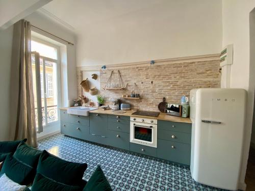 a kitchen with blue cabinets and a white refrigerator at Appartement Haussmannien rue piétonne Opéra in Marseille