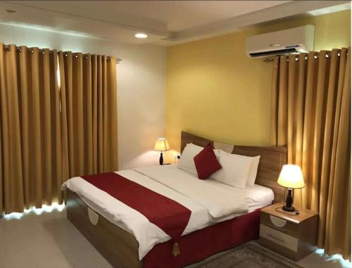 sypialnia z dużym łóżkiem z białymi i czerwonymi poduszkami w obiekcie AL MANAF HOTEL SUITES w Maskacie