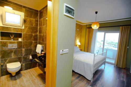 a bathroom with a bedroom with a bed and a toilet at Urla Zeytin Hotel in Urla