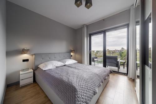 a white bedroom with a bed and a large window at Martinus Apartments in Mechelinki