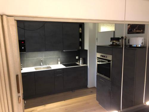 een keuken met zwarte kasten en een wastafel bij Nice Apartment private host Engelberg in Engelberg