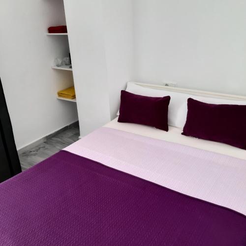 a bed with purple sheets and pillows in a room at Aldea Beach in Castillo de Sabinillas
