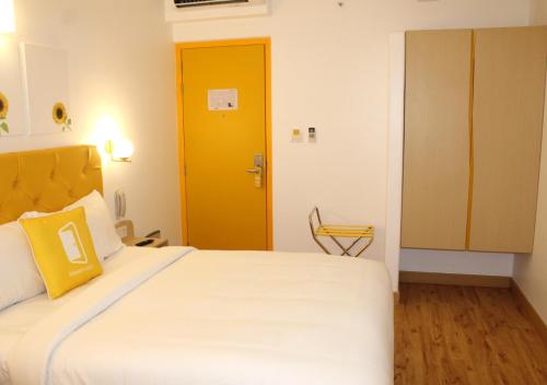 a bedroom with a large bed with a yellow door at Bloom Hotel - Brookefield in Bengaluru