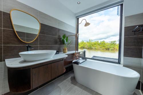 een badkamer met een bad, een wastafel en een spiegel bij SS Villa & Resort in Trâpeăng