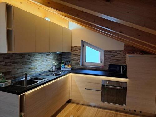 uma cozinha com um lavatório e um micro-ondas em Cadore Luminoso appartamento em Calalzo