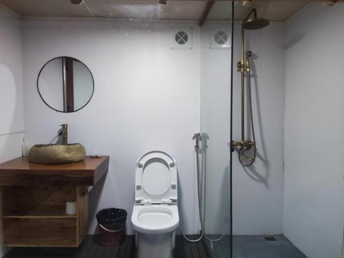 a bathroom with a toilet and a glass shower at Flourish Homestay in Mộc Châu