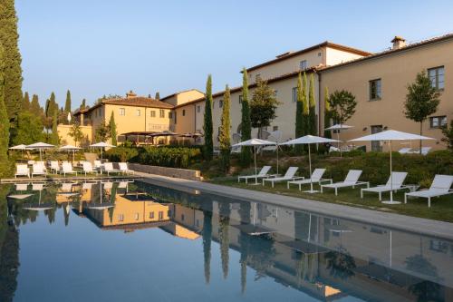 einen Pool mit Stühlen und Sonnenschirmen neben einem Gebäude in der Unterkunft Villa Petriolo in Cerreto Guidi