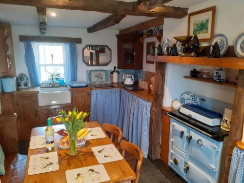 uma cozinha com uma mesa de madeira e um fogão azul em Beautiful 300 year old traditional country cottage em Courtmatrix