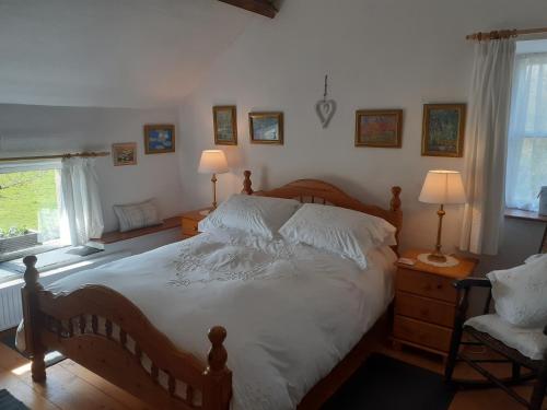 a bedroom with a bed and two lamps and a chair at Beautiful 300 year old traditional country cottage in Courtmatrix