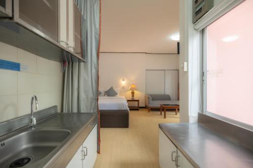 a kitchen with a sink and a bed in a room at Bangkok Rama Hotel in Bangkok