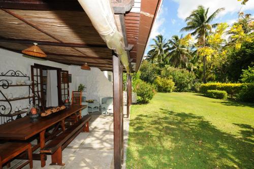 a patio with a wooden table and a grass yard at La Cocoteraie in Le Morne
