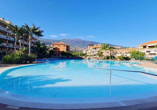 una gran piscina azul con palmeras y edificios en Retama del Teide, Puerto de la Cruz, en Puerto de la Cruz