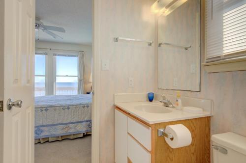 een badkamer met een wastafel, een spiegel en een bed bij Chambless at Ease in Surf City