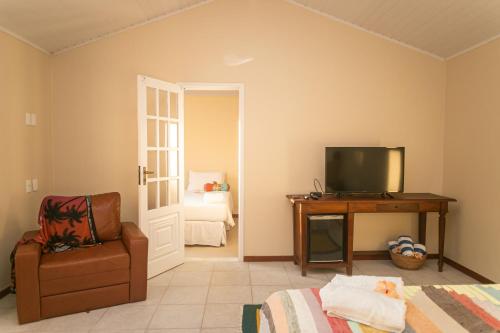 a room with a tv and a chair and a bed at Pousada Corsario Buzios in Búzios