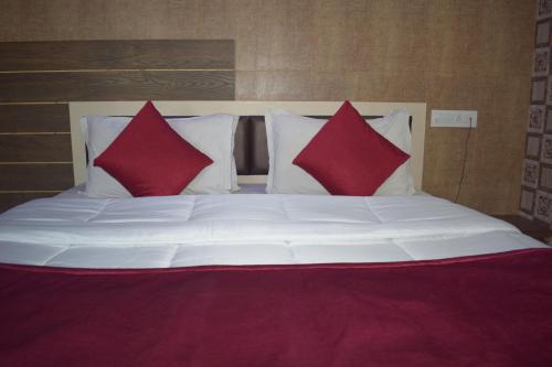 a large bed with two red pillows on it at The Sky Comfort - Hotel The Heaven, Dwarka in Dwarka