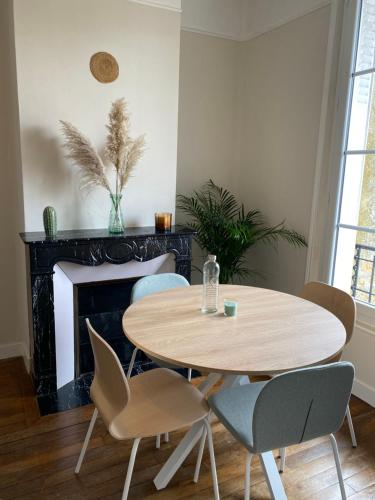 - une table et des chaises dans le salon doté d'une cheminée dans l'établissement Le Cocon Rethelois., à Rethel