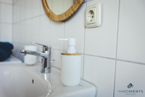 ein Waschbecken mit einem Seifenspender und einem Spiegel in der Unterkunft Serviced Apartment mit Netflix und WLAN im Zentrum in Magdeburg