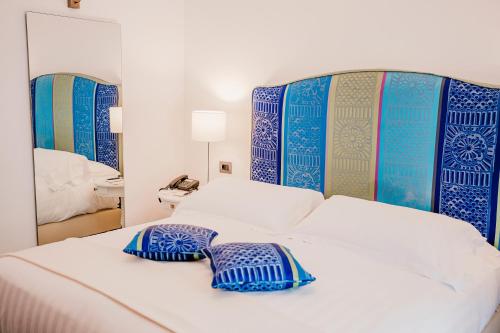 a bed with blue and white pillows and a mirror at San Montano Resort & Spa in Ischia
