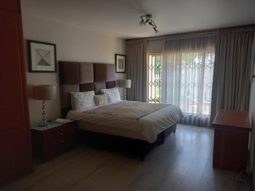 Un dormitorio con una cama grande y una ventana. en Mount Royal 02 Large 3 bedroom Ground floor apartment with Garden, en Johannesburgo