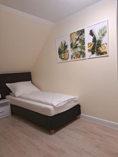 um quarto com uma cama com duas fotografias na parede em APARTAMENT SZMARAGD em Zastań