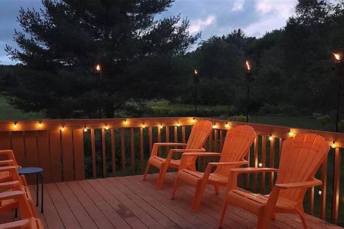 a deck with chairs and lights on a fence at Beautiful mountain home with gorgeous meadow views in Hunter