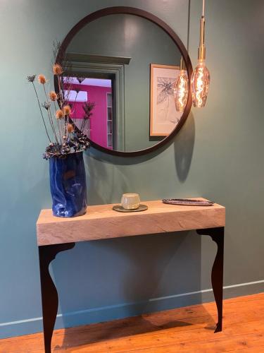 - une table avec un miroir et un vase bleu dans l'établissement Suite avec Spa Quartier Cathédrale, à Autun