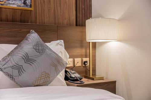Zimmer mit einem Bett, einer Lampe und einem Telefon in der Unterkunft DiYar Home Hotel in Baljurashi
