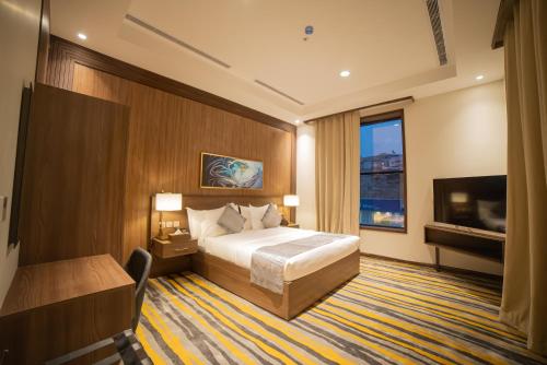 a hotel room with a bed and a television at DiYar Home Hotel in Baljurashi