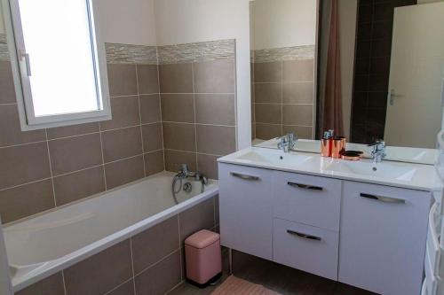 une salle de bain avec une baignoire et un lavabo et une baignoire dans l'établissement VILLA avec PISCINE chauffée trois chambres, à Saint-Sulpice-de-Royan