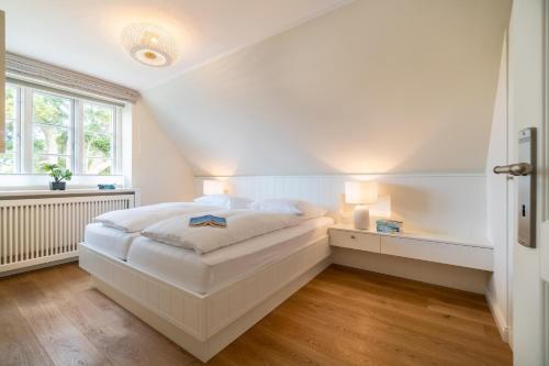een witte slaapkamer met een bed en een raam bij Caras Hus in Midlum