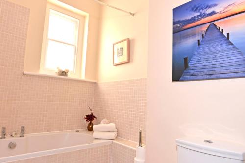 La salle de bains est pourvue d'une baignoire et d'une peinture murale. dans l'établissement Cavendish apartment - central and spacious, à Eastbourne